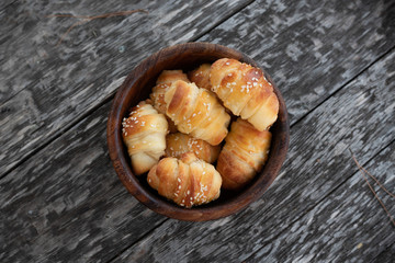 Croissants sprinkled with sesame seeds in a wooden basket. Close-up