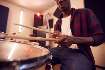 Cropped portrait of young African-American man playing drums with contemporary music band during...