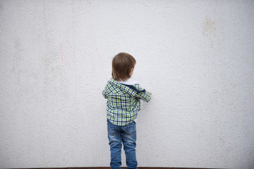 Boy stand facing a white wall. Blurred image - 316641431