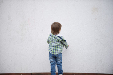 Boy stand facing a white wall. Blurred image - 316641445