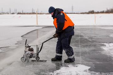 Worker cuts out ice blocks in size on the ice of a frozen lake