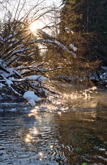 Obraz na płótnie Canvas Sunburst in winter with flowing river