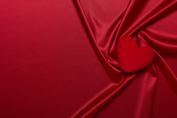 Abstract background from red silk (satin) and heart. Fabric texture with draped. Copy space. Element design. Valentine's day.