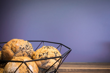 Selbst gebackene Brötchen in einer Schüssel auf einem Holzuntergrund mit freiem lilanen Hintergrund für eigenen Text 