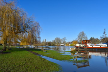 Fototapeta na wymiar Thames path flooded. Benches garbage bins in water. Trail becomes rural into Shiplake where it leaves the river before arriving in Sonning. It switches banks to the busy town of Reading in Oxfordshire