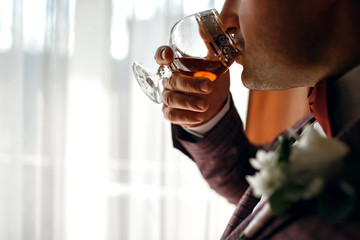 Stylish man with a glass of whiskey, an attractive man drinks cognac