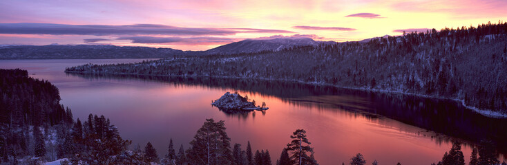 This is Emerald Bay at sunrise after a winter snow storm. There is snow on the land surrounding the bay. - obrazy, fototapety, plakaty