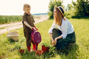 Family gardening. Lady in a green dress. Mother with little son