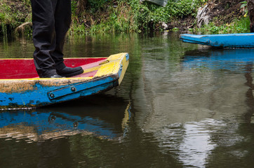Fototapeta premium Xochimilco, Mexico; legs of a man at the end of a trajinera boat