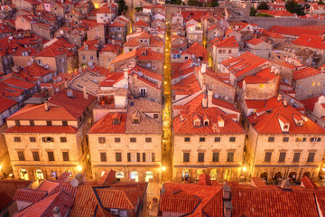 Fototapeta na wymiar Aerial view of houses with red roofs at night in Dubrovnik, Croatia. Top view of beautiful architecture in old city. City lights, historical centre, buildings, walking people in illuminated streets