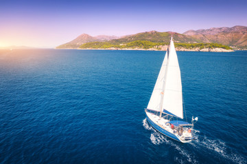 Aerial view of beautiful white sailboat in blue sea at bright sunny summer evening. Adriatic sea in...