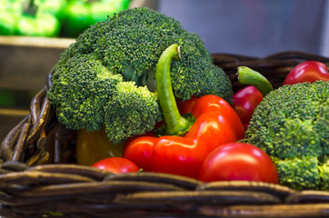 set of vegetables, broccoli cabbage, red bell pepper, tomatoes in a wicker basket on a store counter, market. harvesting. vitamin, healthy eating, soft focus
