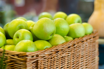 ripe, juicy green apples in a wicker basket on a store counter, market. harvesting. vitamin, healthy eating, soft focus