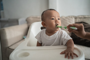 Little asian child eating rice soup from mother feeding