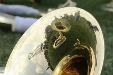 Students at a marching band camp are reflected in the bell of a tuba.