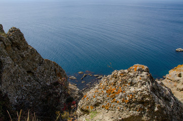Rocky sea coast, view from the top of the cliff and stones near the water. Travel and adventure.