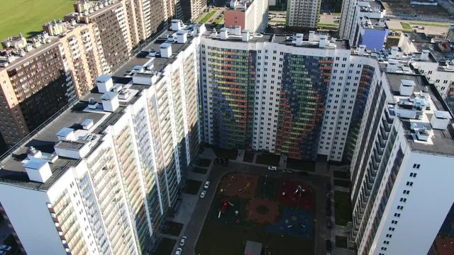 Aerial view of the modern complex of apartment residential buildings with colorful facades, new children playground and other developed infrastructure. Motion. Beautiful new residential complex