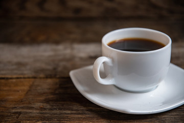 White cup of espresso coffee on a wooden background.