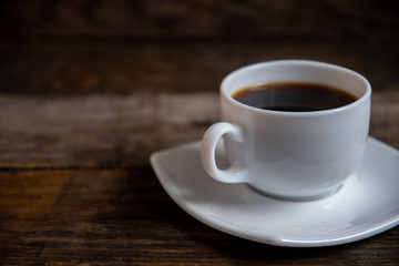 White cup of espresso coffee on a wooden background.