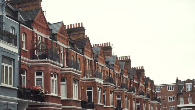 Close-up of Row of typical English terraced brick houses against the grey sky in autumn day. Action. Traditional English architecture