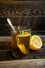 Tea with lemon in a glass on a wooden background.