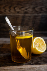 Tea with lemon in a glass on a wooden background.