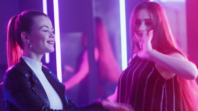 Neon girls. Clubbing lifestyle. Happy female friends enjoying dancing in purple glow.