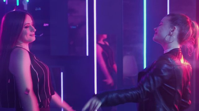 Neon women. Girls night. Joyful female friends dancing in confetti rain purple illumination.
