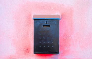 Simple black mail box centered on a pink wall.