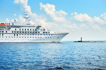 Large white passenger ship in the Baltic Sea, close-up. Lighthouse in the background. Riga bay,...