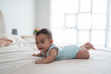 Cute happy 4 month baby lying on belly playing on the bed