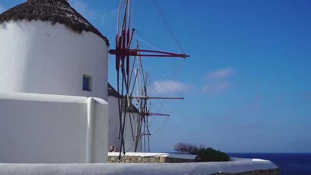 Sliding reveal of the famous windmills of Mykonos with the Aegean sea in the background and no people around
