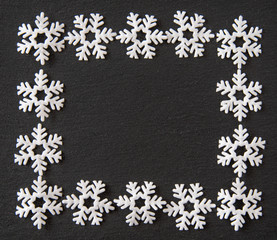 Felt snowflakes in a framed border on dark gray slate as a background