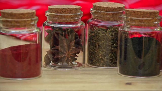 Selection of Jars with dried spices laid out in a row on wooden table. pan right 