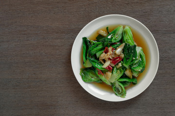 top view of stir fried cabbage sprout with soy sauce in a ceramic dish on wooden table. homemade style food concept.