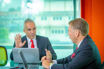 A Businessmen  wearing suit looking at laptop computer and paper of work discussing for work diagram in office company with business meeting concept
