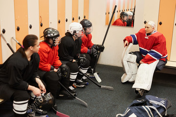 Portrait of female hockey team captain giving motivational pep talk in locker room before match,...