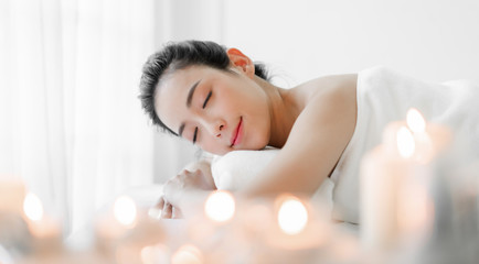Beautiful young woman beauty skin treatment relaxing lying on towel in massaging and spa salon