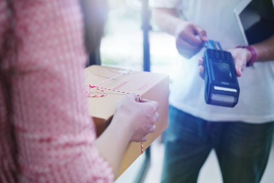 Man with credit card using bank terminal for delivery payment at doorway.