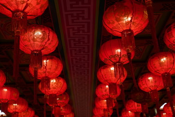 Many illuminated red Chinese lanterns with some Chinese characters on it in temple - Used across countries in Asia for celebrating Chinese New Year tradition