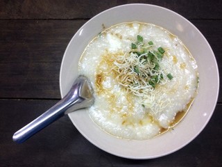 Pork congee, add egg, garnished with sauce and vegetables
