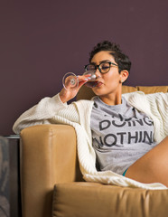 A woman relaxes on a leather couch with a glass of wine