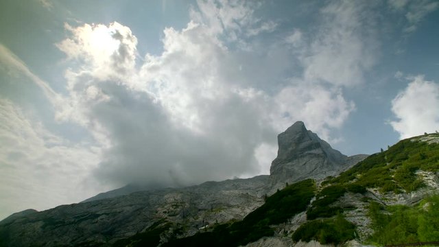 Clouds twirling over huge rocky mountain obscuring the sun, timelapse, Dolomites, Italy, High quality 4k prores
