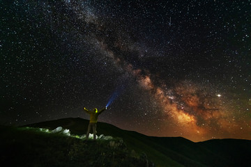 Fantastic starry night with galaxy Milky Way with a tourist and a tent on the mountain range in the Ukrainian Carpathians	