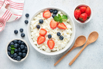 Cottage cheese, curd cheese with fresh summer berries in a bowl, table top view. Healthy dairy...