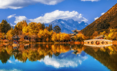 Panorama Landscape view of the Black Dragon Pool at Jade Spring Park with marble bridge over the Jade dragon mountain under blue sky, Lijiang, Yunnan province, China. China culture and travel concept - obrazy, fototapety, plakaty