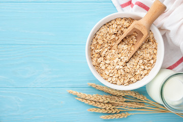 Oats and oat milk on blue wooden background, top view copy space. Bowl of uncooked dry oat flakes. Concept of dieting, healthy eating, weight loss and fitness food menu
