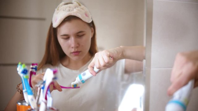 A young woman applying toothpaste on the brush