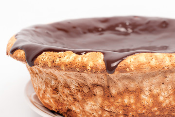 flowing chocolate on the sides of the cake. sponge cake with caramel pouring around the edges on white background close up