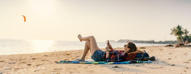 Young woman lying with smart phone on a beach. Relaxation concept